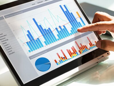 Close-up of a businessman's hand analyzing graphs on laptop at workplace.