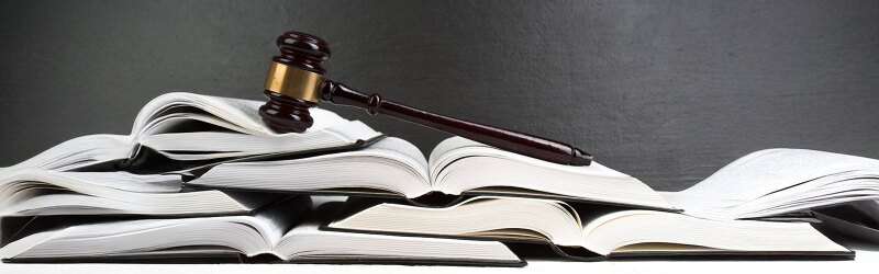 A gavel is on top of a pile of open books.