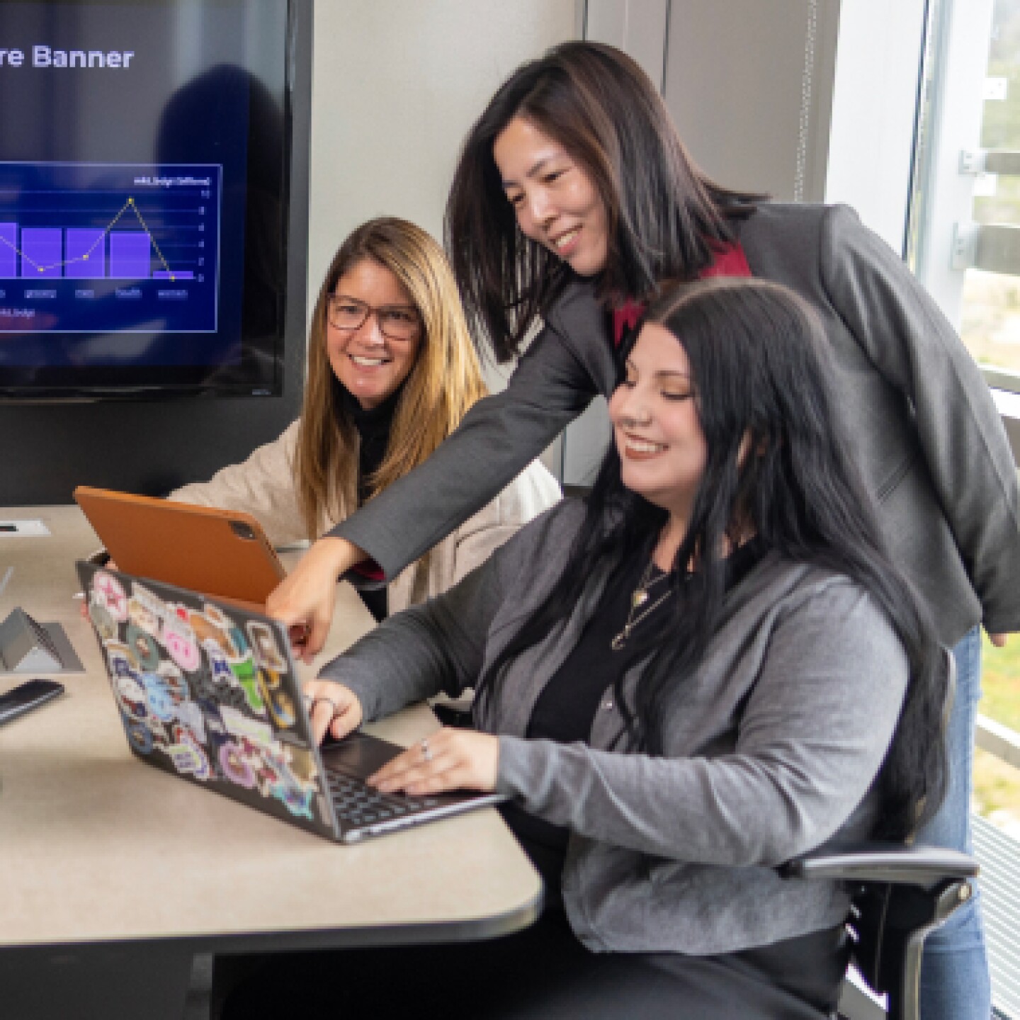 A female CSUMB professor leaning over table to assist two female students.