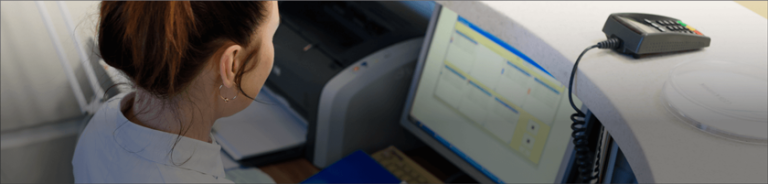 Woman seated at reception desk looking at laptop screen