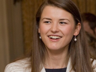 Young woman speaks with another woman and a man at a networking event.