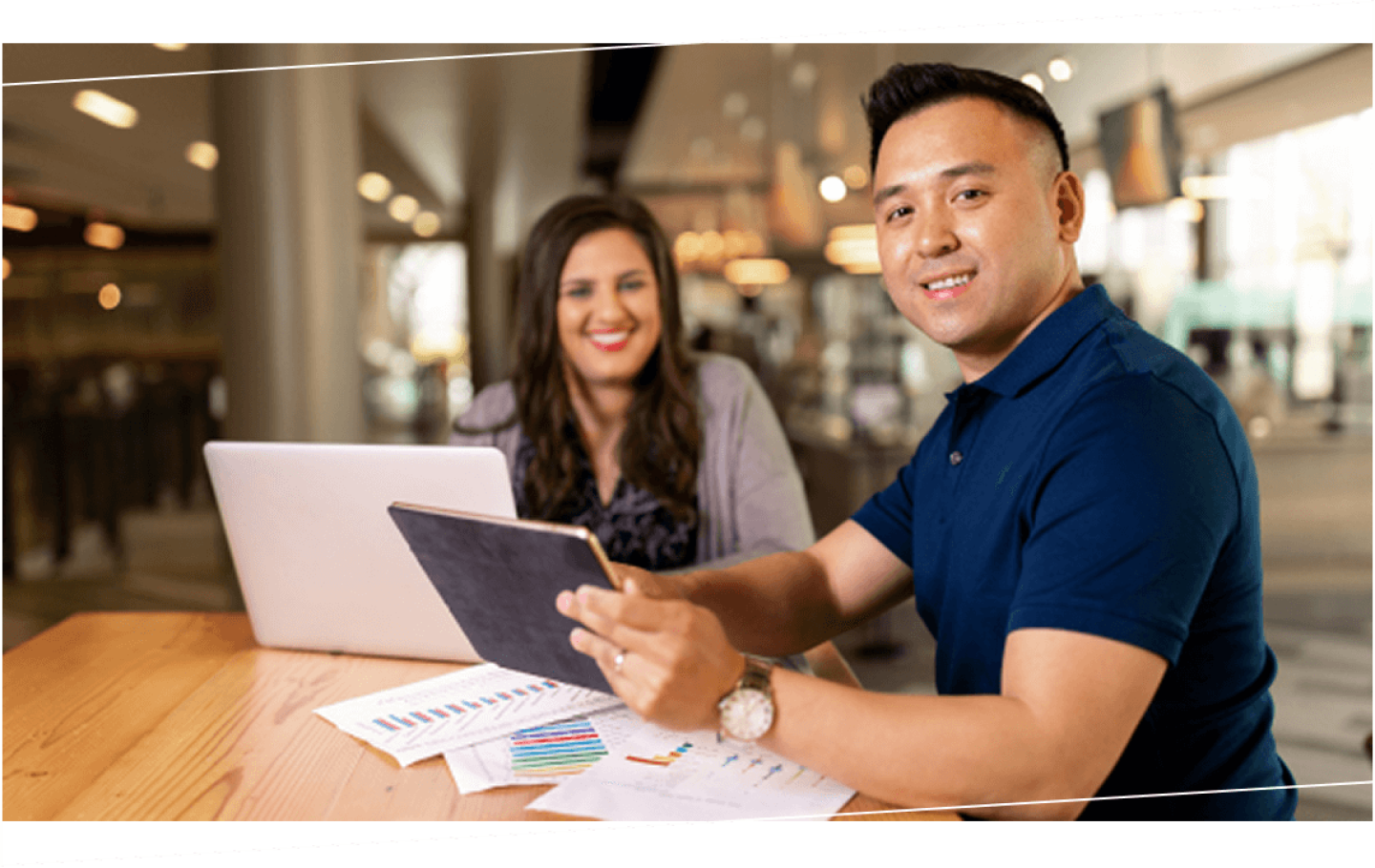 Man and woman with tablets looking over bar graphs together