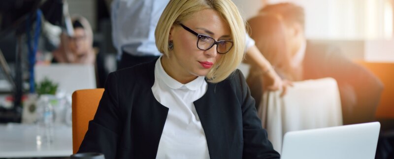 Concentrated businesswoman focused on laptop in office environment