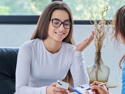 Young smiling girl patient in therapy session with social mental therapist.