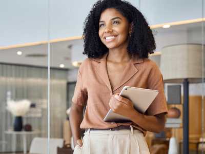 Smiling African American female standing in an office holding a laptop