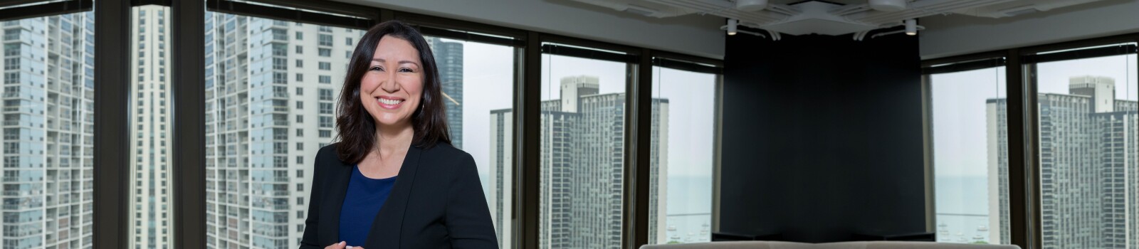 IMC alumni stands in office space while wearing a black blazer