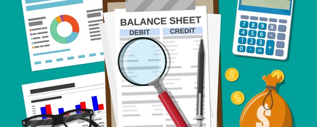balance sheet on desk with calculator and magnifying glass