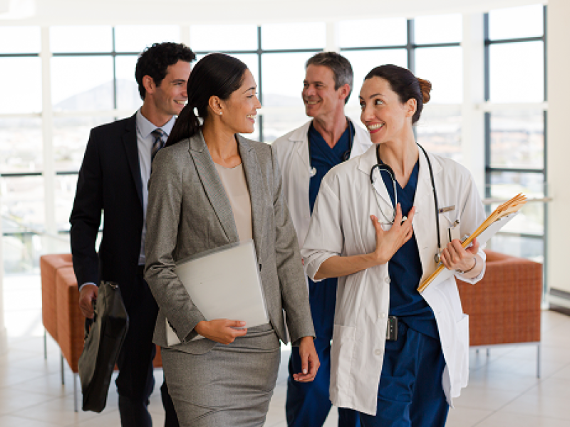 Group of Business and Medical professionals communicating through the hallways of a hospital