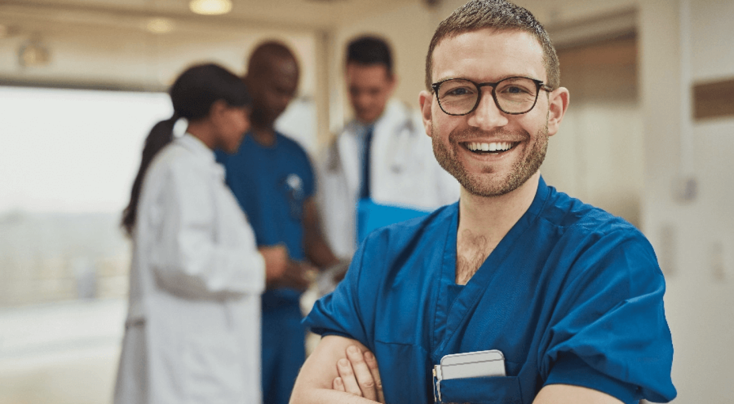 Male nurse in glasses with arms crossed smiling