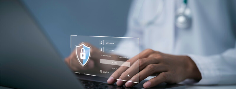 Close-up image of a doctor's hands typing on a laptop. A digital image depicts a login screen.