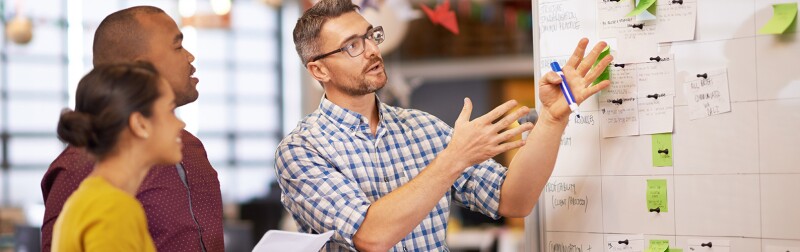Group of coworkers brainstorming at a whiteboard