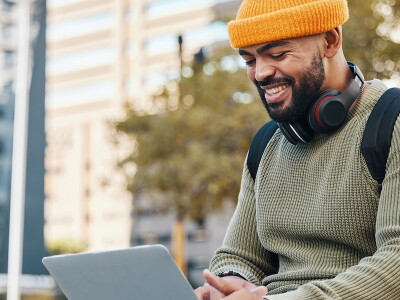 A man works remotely on a scholarship application on his laptop in the middle of the city.
