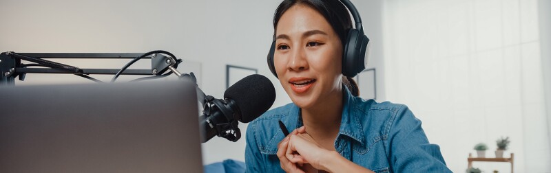 Female podcaster make audio podcast from her home studio.
