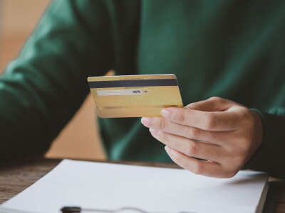 An individual holds a credit card while making a purchase on an online shopping website.