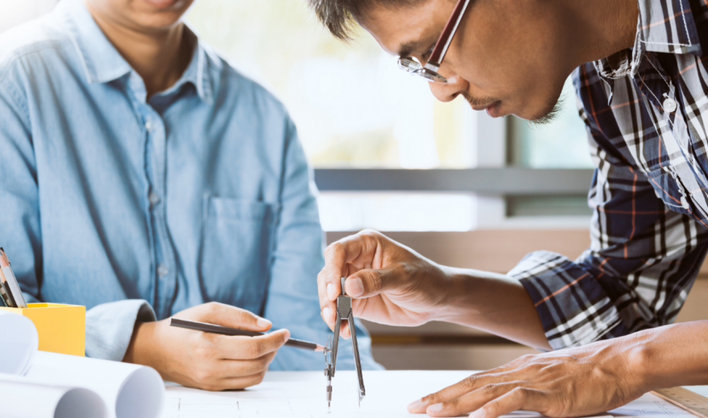 Two men working on blueprints
