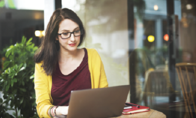 girl with long brown hair and glasses working on computer