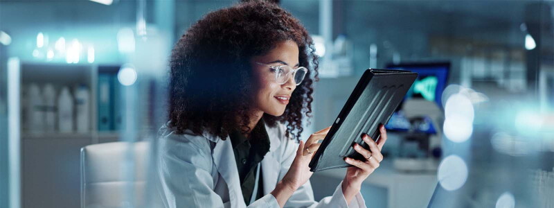 Medical professional reviews data on a tablet.