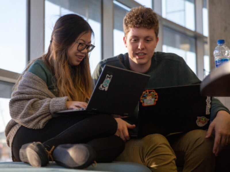 A male and female KU student review lessons on a laptop.