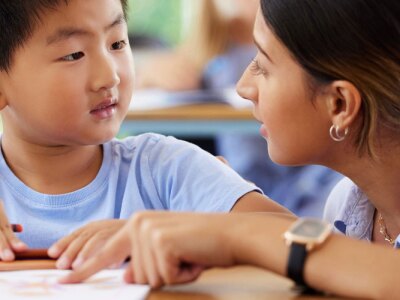 Teacher helping student in classroom with an assigned reading.