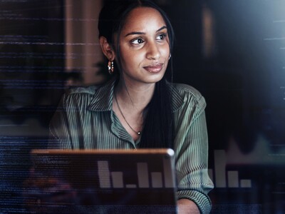 Woman thinking at a laptop with computer data as an overlay