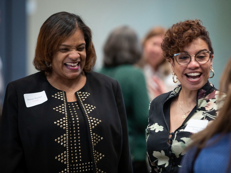 Two women with nametags laughing during conference