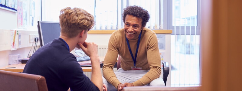 A counselor smiles encouragingly while listening to a young client