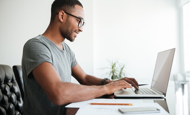 Young Black man using laptop and sitting at desk