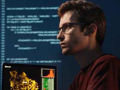 An engineer focused on code on multiple monitors.