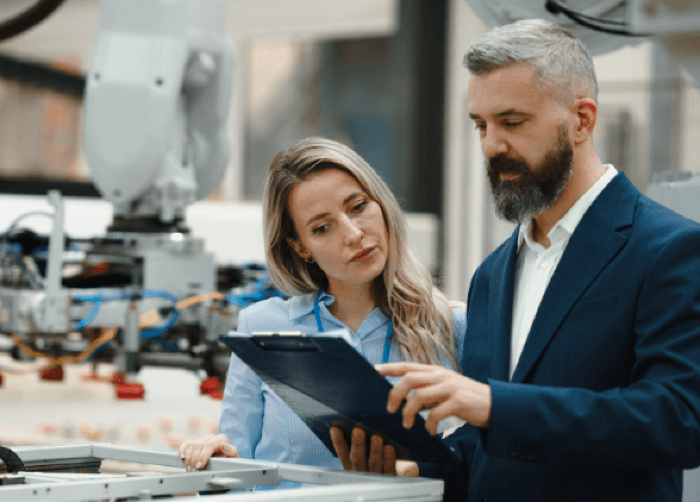 Man and woman in factory looking at clipboard