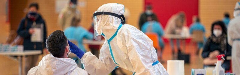 Health workers in protective suits are engaged in salivary and nasal tests inside a public gym.