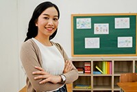 Confident teacher standing in front of classroom with arms crossed