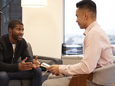 two men sitting across from each other having a discussion