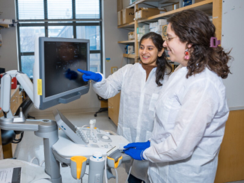 Two female CWRU biomedical engineering students review analytic metrics on computer screen.