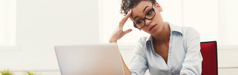 Frustrated business woman sitting behind office desk.