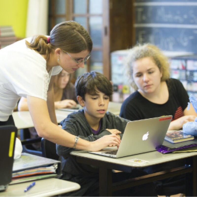 Female educator works with student on laptop