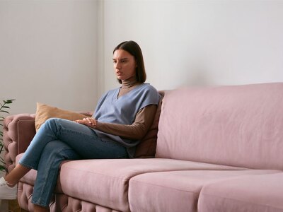 male counselor taking notes in session with female patient sitting on pink couch