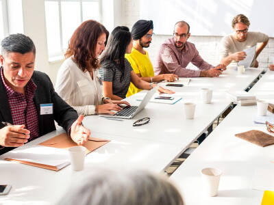 Diverse colleagues carry on collaborative discussion around a meeting table