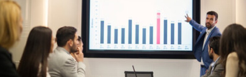 man-in-blue-suit-presenting-blue-and-red-bar-chart-to-audience