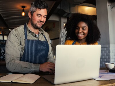 Coffee shop ownerss reviewing analytics data on a laptop