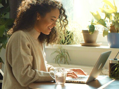 Young woman typing on laptop computer in a kitchen