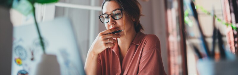 Young woman thinking while sitting in front laptop computer