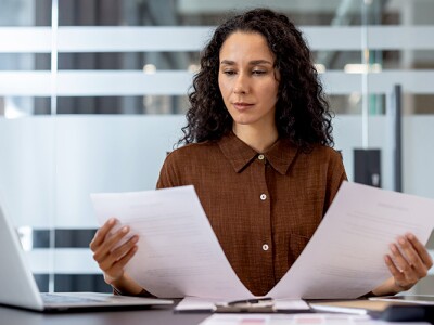 Woman at her desk comparing two financial documents.