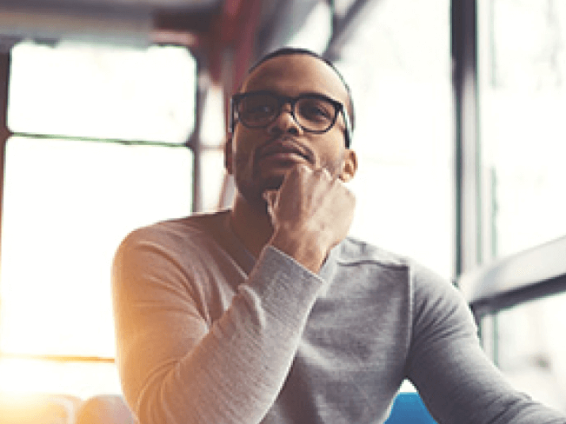 Man in glasses thinking with hand on chin