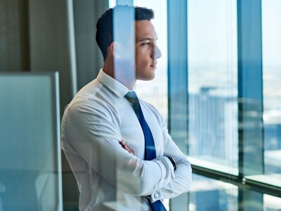 Confident accountant looking through windows at the city from high up in an office building