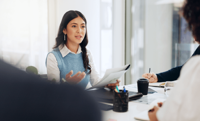 Woman in business attire leading a discussion at meeting table