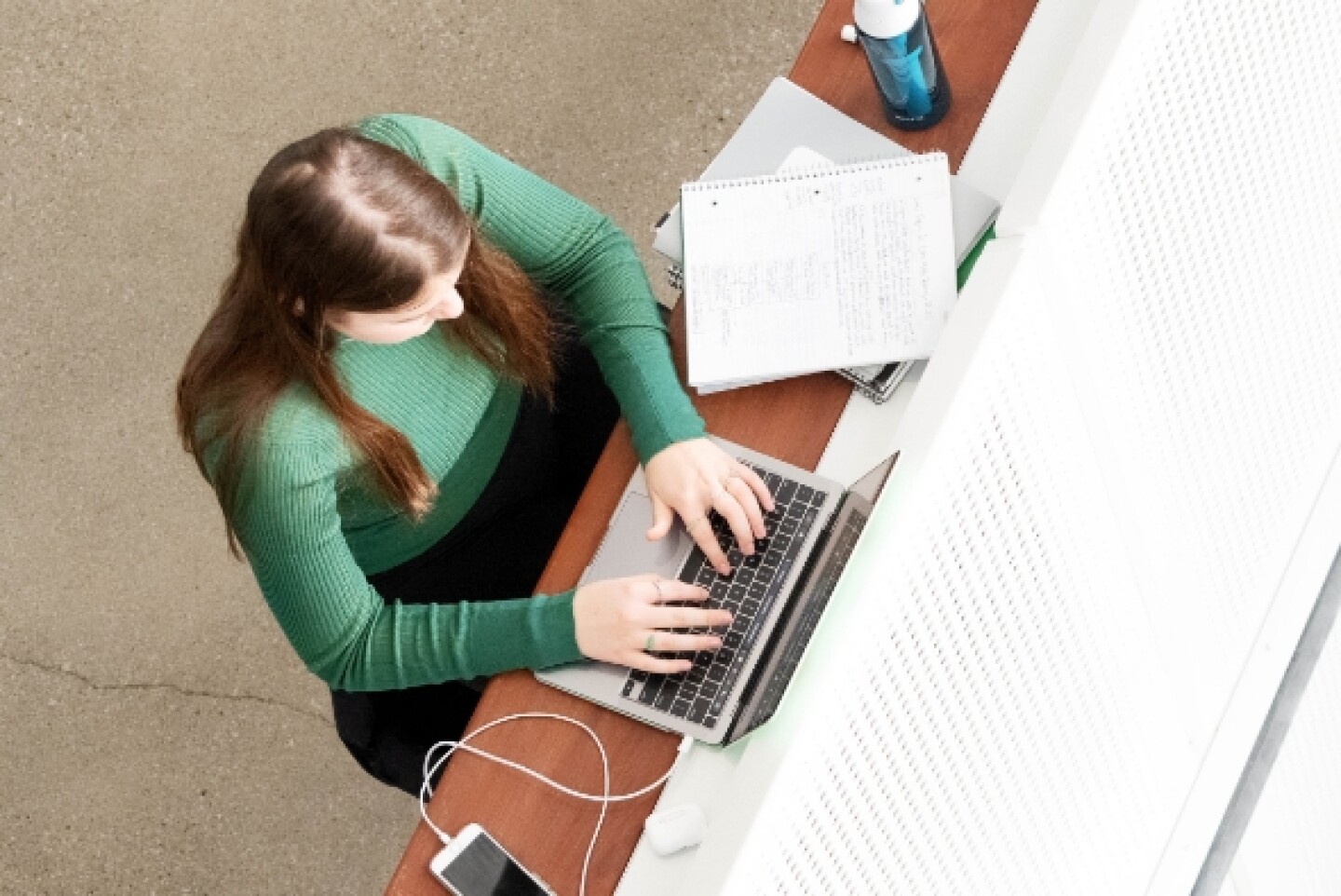 Overhead view of female student seated at desk with laptop