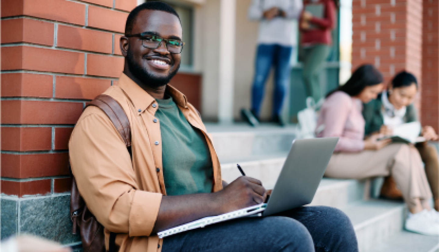 A smiling male CWRU student sitting on stairs outside the campus building.