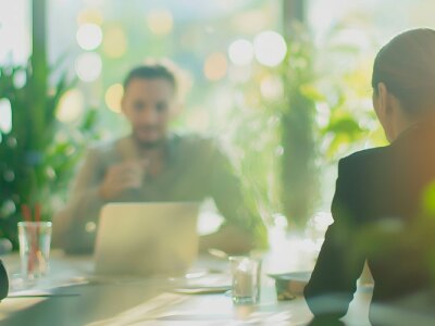 Team of business professionals is having a productive meeting in a modern office filled with natural light and lush green plants.