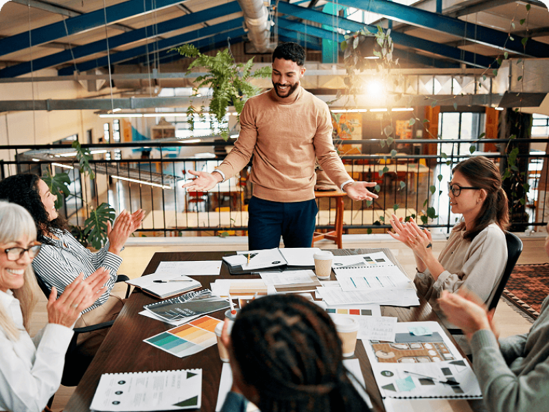 Group of colleagues applauding during man's presentation a conference table