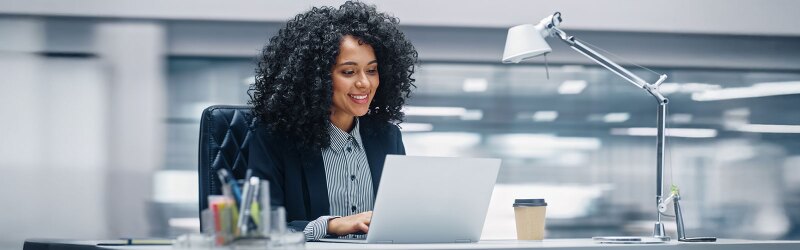 Black businesswoman sitting at her desk working on a laptop computer